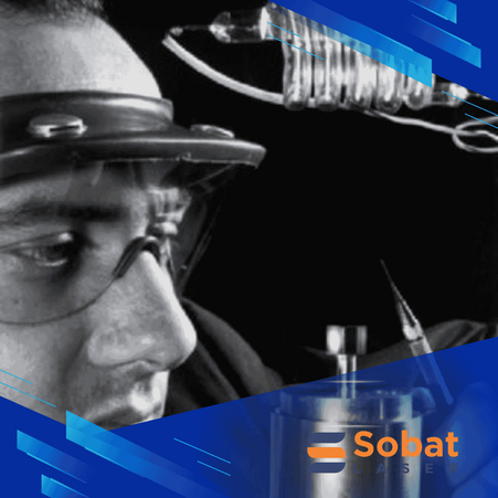 Theodore H. Maiman memegang laser ruby pertama di dunia tahun 1960, penemuan awal teknologi laser modern.